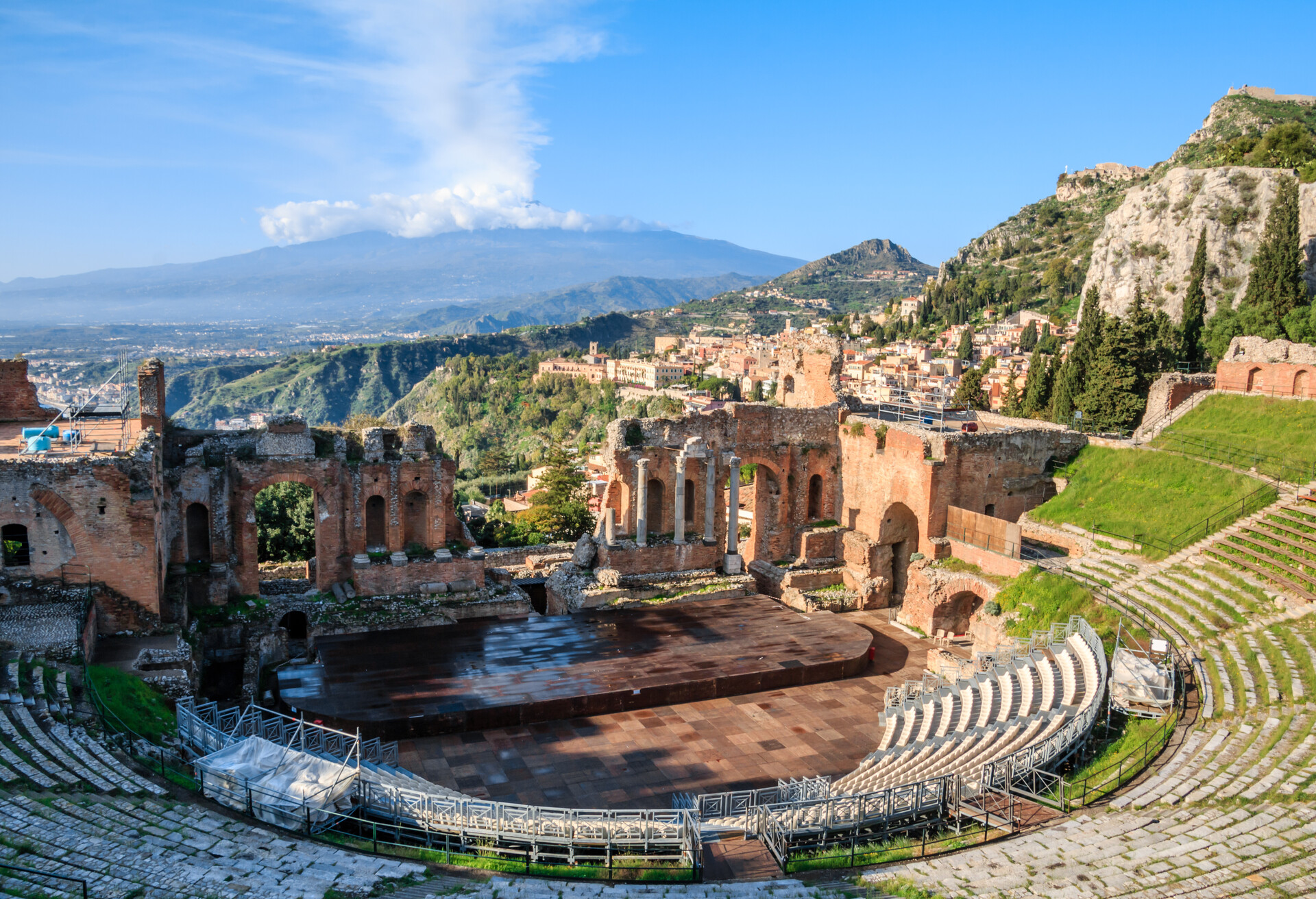 The Greek theatre with smoking Mount Etna volcano in the background, Taormina, Sicily, Italy.